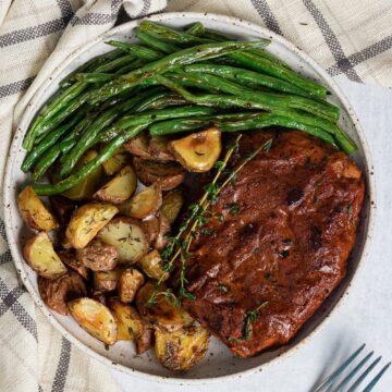 overhead view of vegan steak with potatoes and asparagus on a white plate