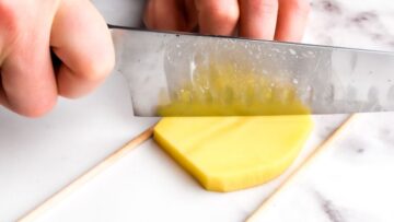 hand cutting diagonal lines in a potato