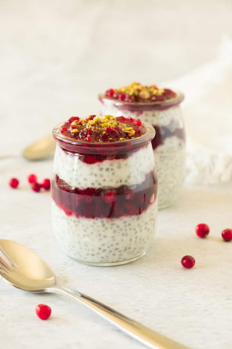 two jars of cranberry chia pudding on a white table