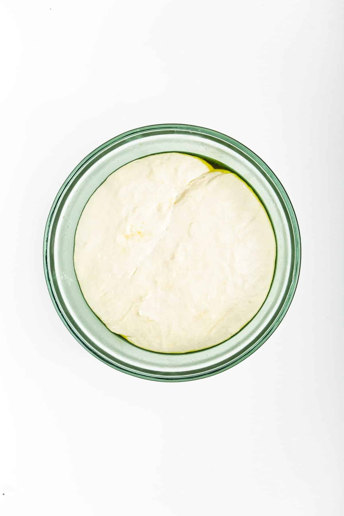 dough placed in a bowl with olive oil to rise