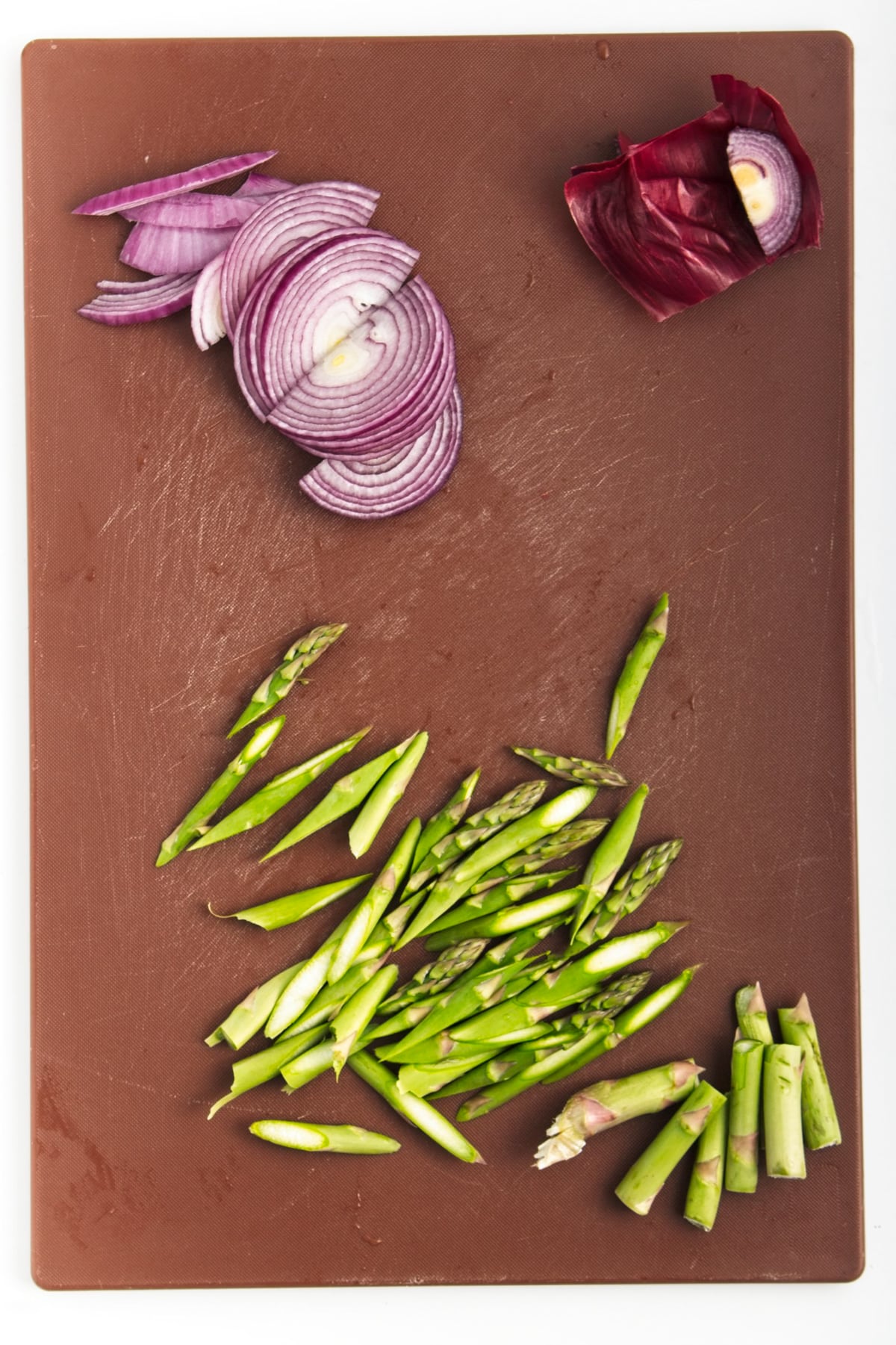 sliced red onion and asparagus stems on a cutting board