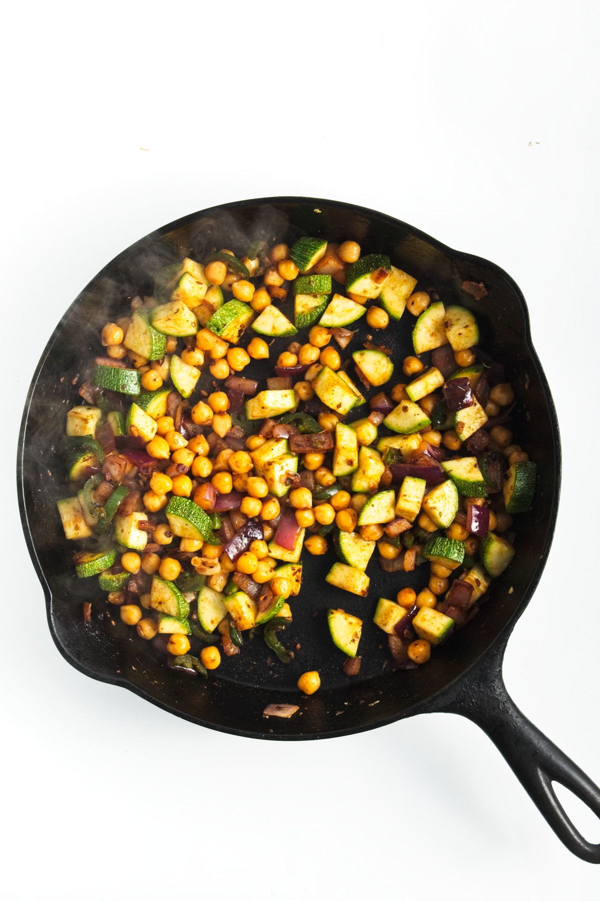 cooked veggies and chickpeas in a cast iron skillet