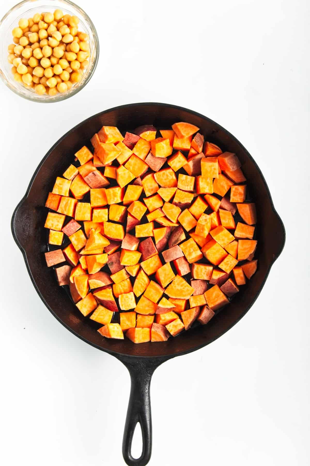 chopped sweet potatoes in a black skillet ready to be cooked