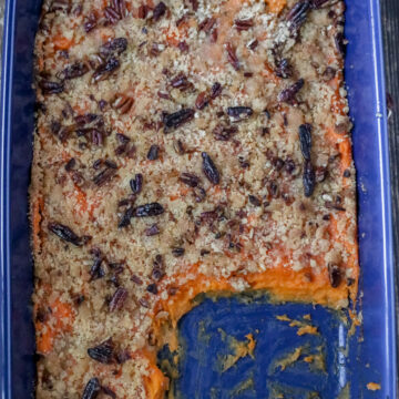 overhead view of sweet potato casserole in a blue dish with a scoop removed