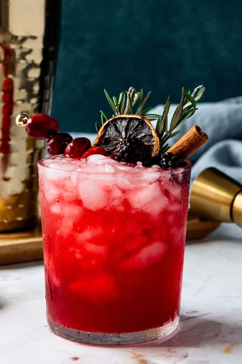 Blackberry Smash Cocktail with beautiful garnishes on a white table