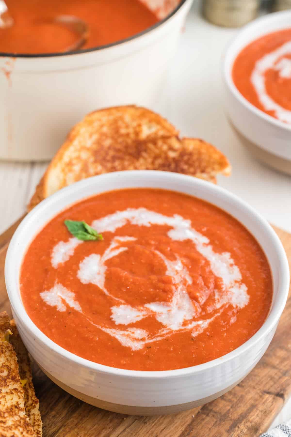 vegan tomato soup in a white bowl with a swirl of coconut milk