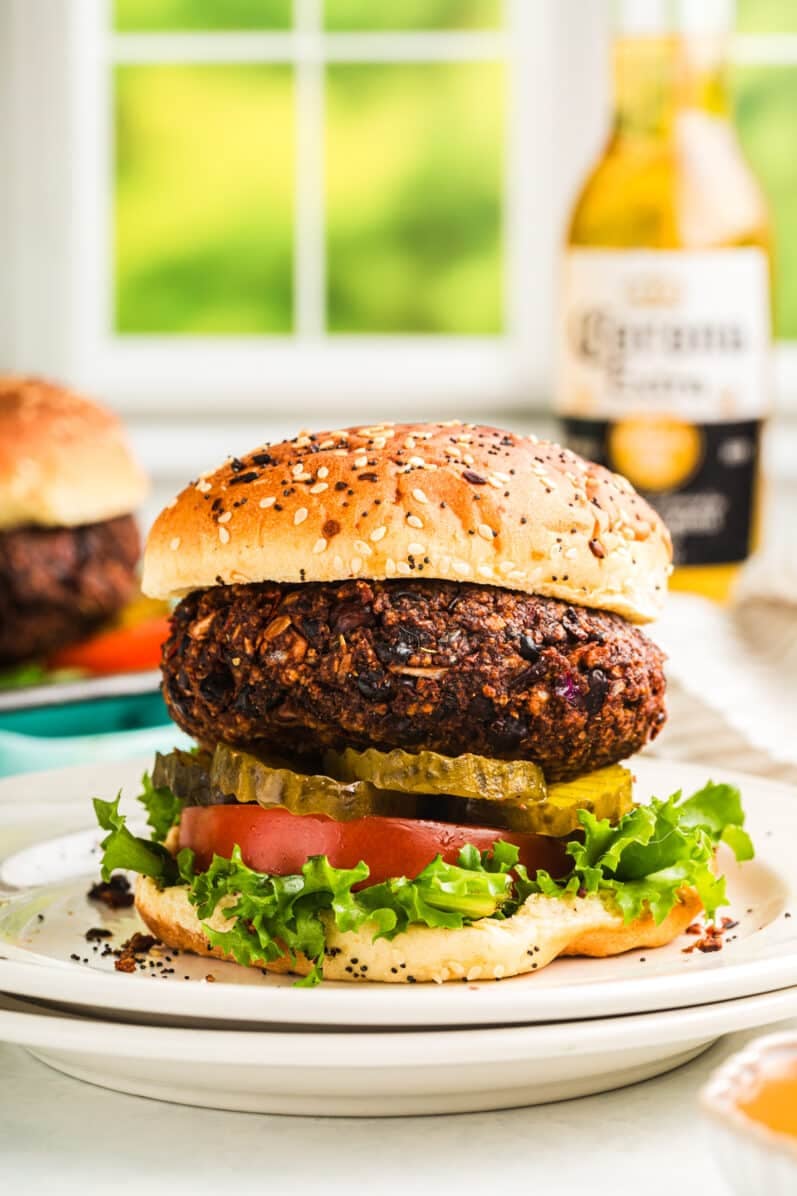 vegan black bean burger with lettuce tomatoes and pickles with a seedy bun