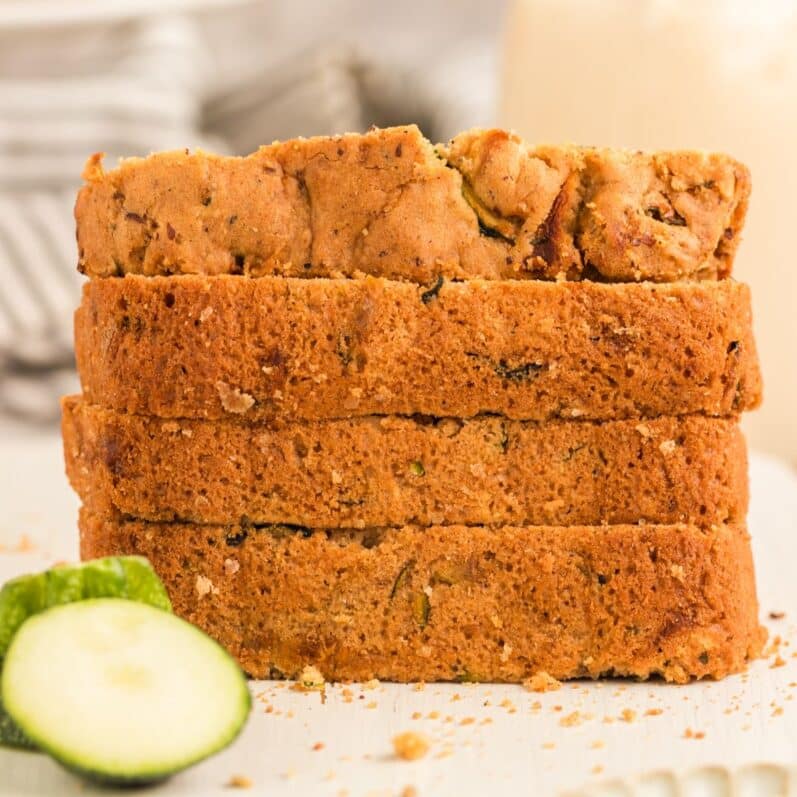 stack of 4 slices of vegan zucchini bread on a white cutting board