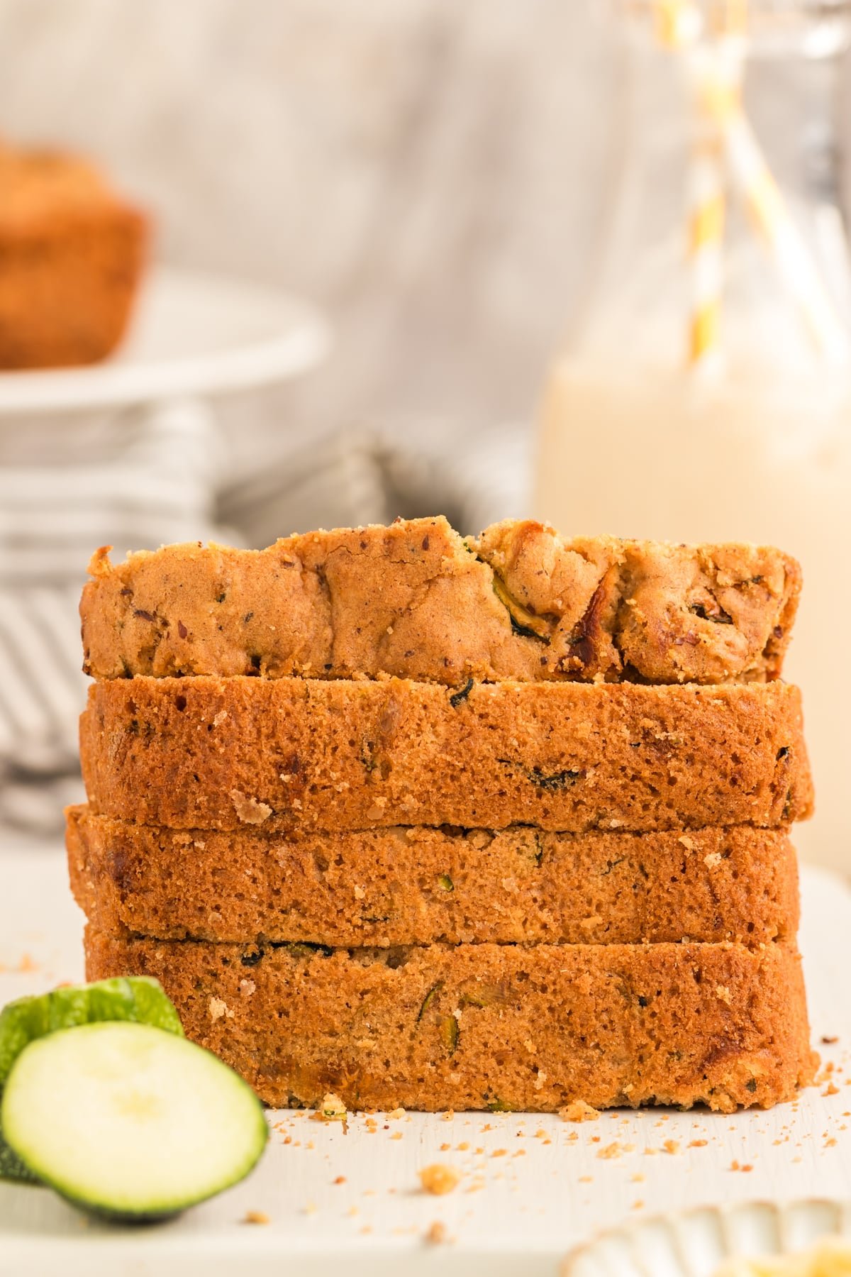 stack of 4 slices of vegan zucchini bread on a white cutting board