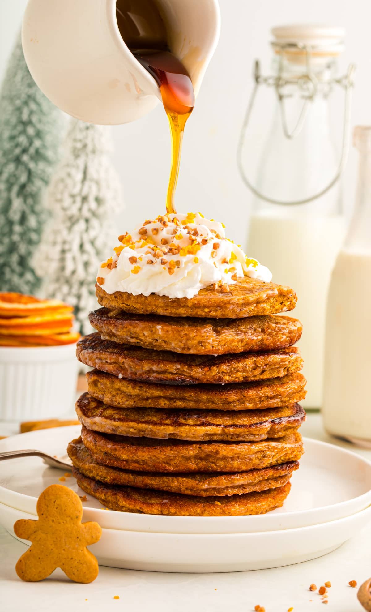 maple syrup being poured over a stack of vegan gingerbread pancakes