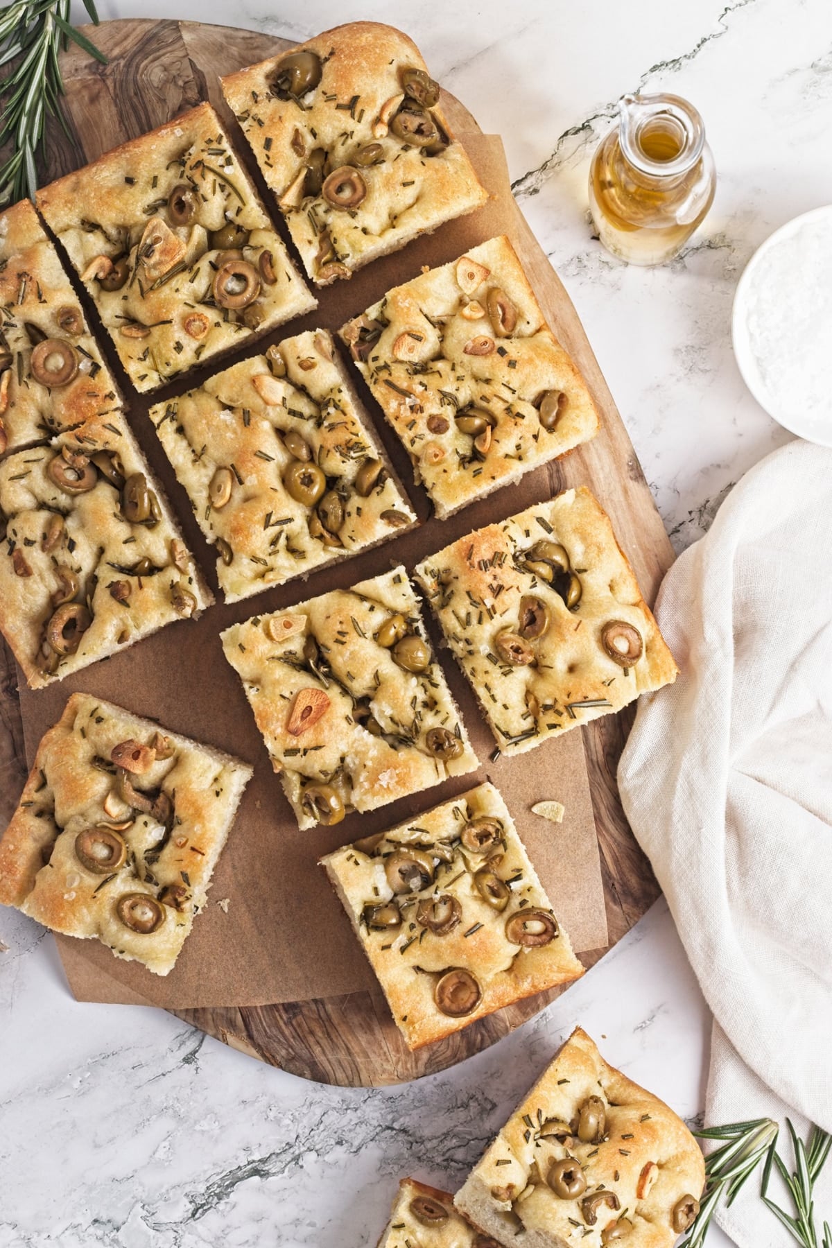 cutting board with slices of garlic and rosemary focaccia on a marble table