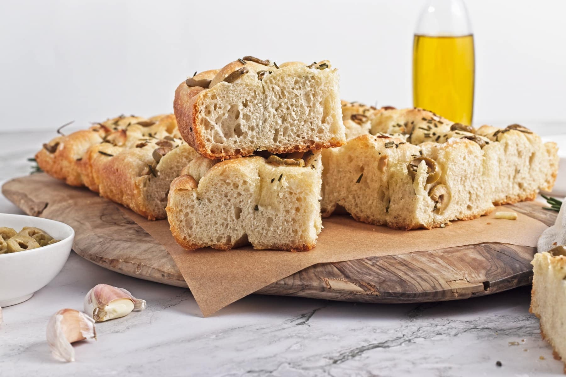 horizontal photo of rosemary and garlic focaccia stacked on a cutting board