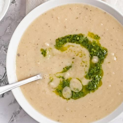 overhead view of turnip soup in a white bowl with garnish of zhoug sauce