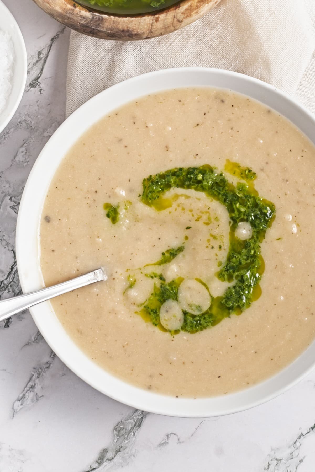 overhead view of turnip soup in a white bowl with garnish of zhoug sauce