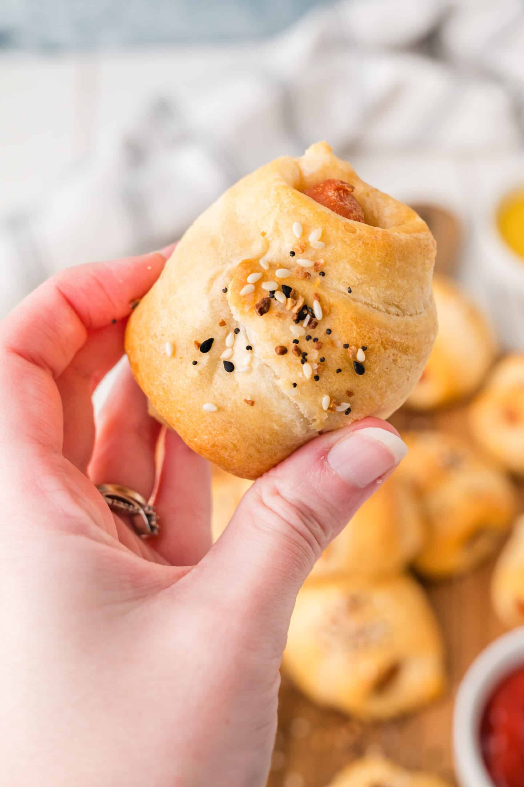 hand holding baked pigs in a blanket made with carrots