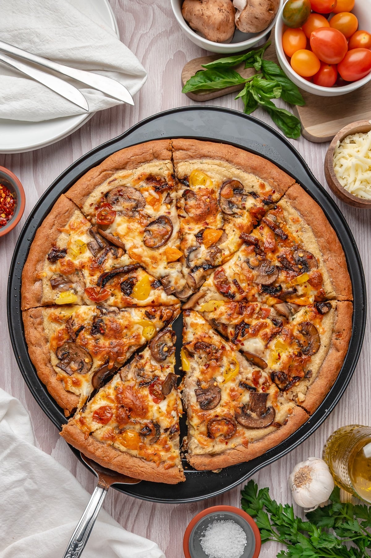 vegan pizza on a pizza pan with a slice cut out