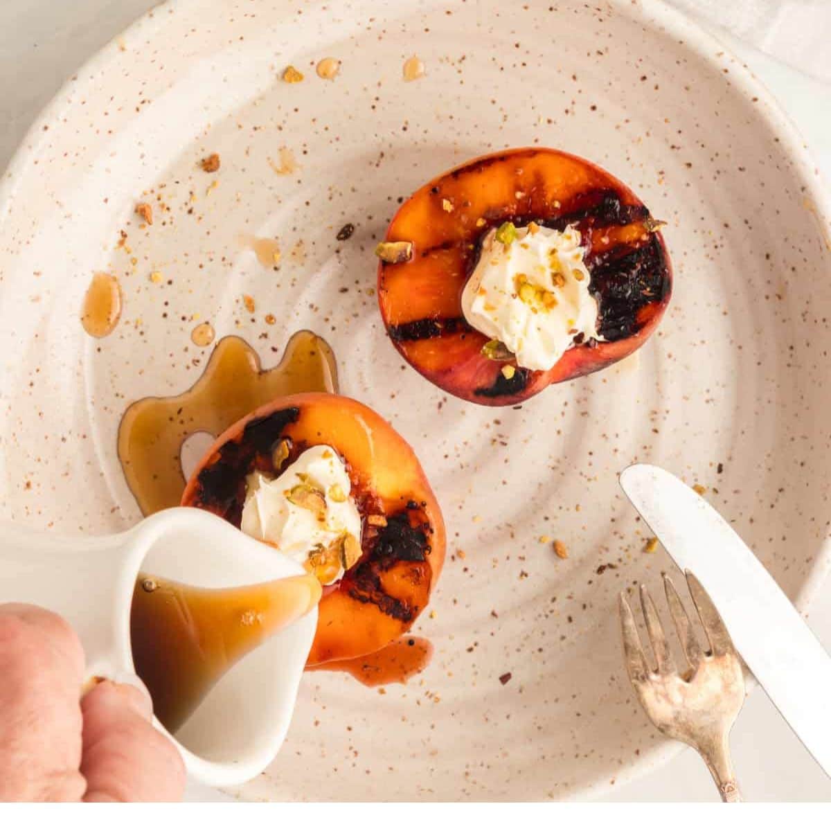 overhead grilled peaches dessert on a white speckled plate