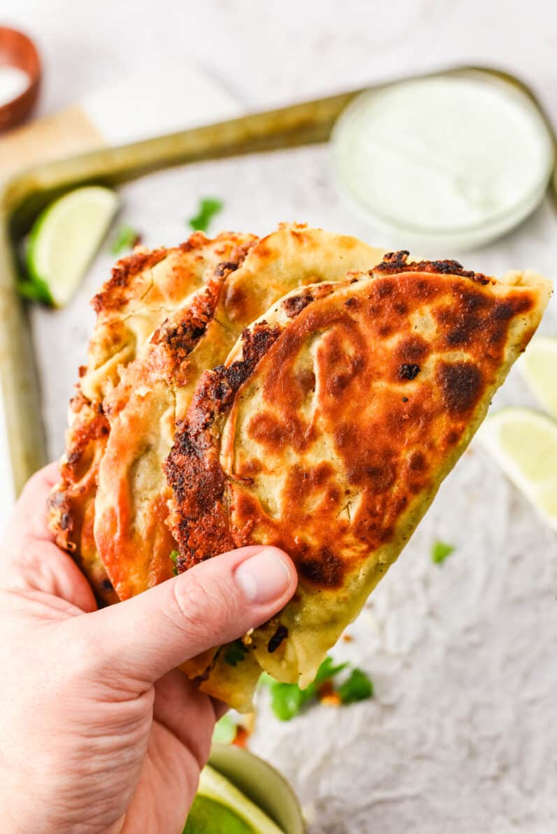 hand holding a couple vegan refried black bean tacos